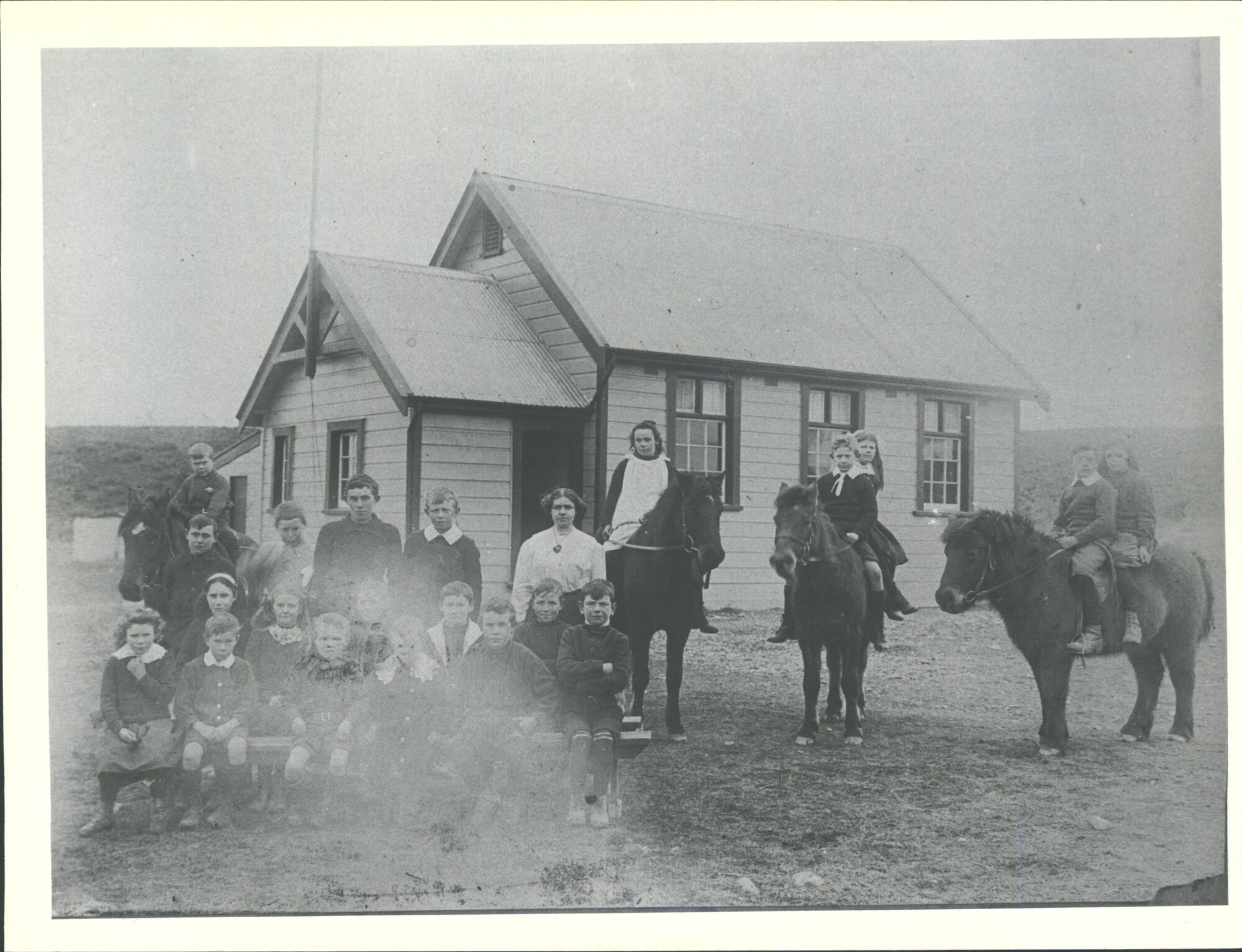 School   Teacher - Miss O'Connor. On ponies:L. Tom Corrigall, Elsie Brown, Alpheus Hayes with sister Meta &amp; Hobbs. Standing: Bus