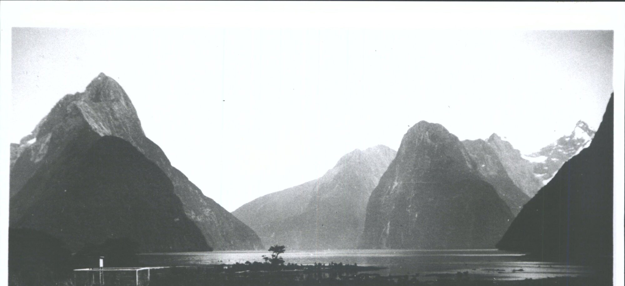 "From front of the Milford Sound Hotel, looking down the Sound, Mitre Peak on left, Lion Rock on right, Pembroke Peake on extrem