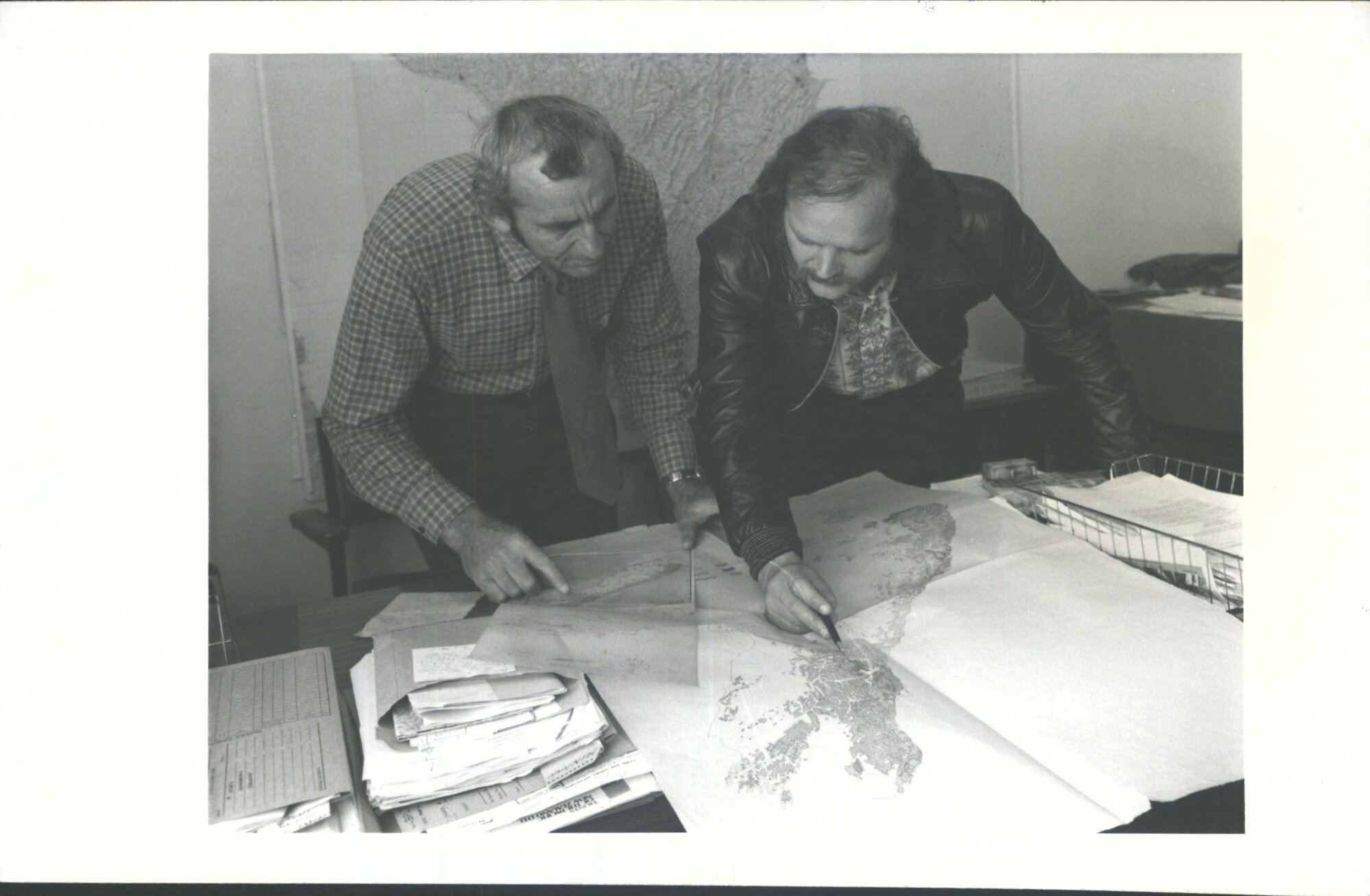 Mr. G. Jeune, left, discusses a mapping problem with chief assistant, Mr. B. K. Bradley.