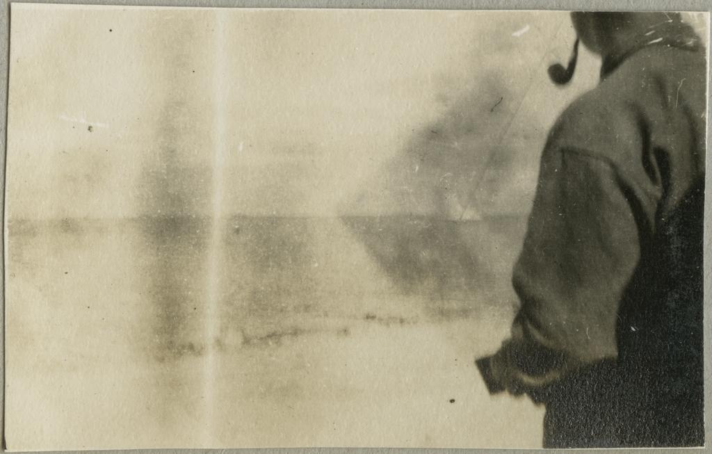 Man with a pipe standing on a shore