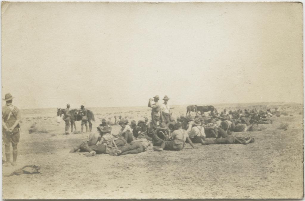 A large group of men, mostly lying or seated on the ground