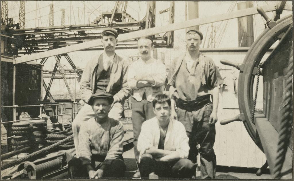 Group of five men next to the wheel on a ship