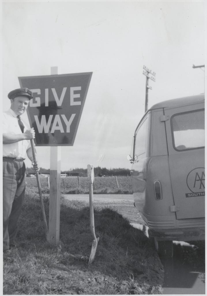 AA patrol officer Erikson with tools, give way sign, and van