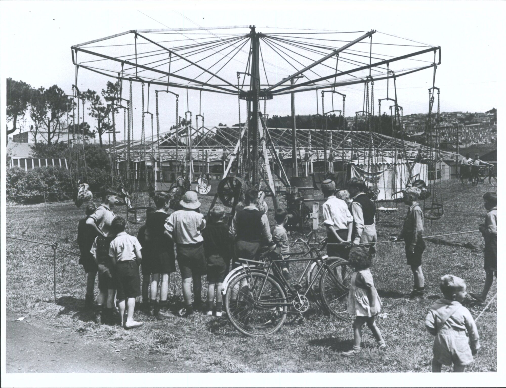 "Children watch with interest the work of preparing entertainment devices [?] for the fun fair"Shows southern end of the Oval w