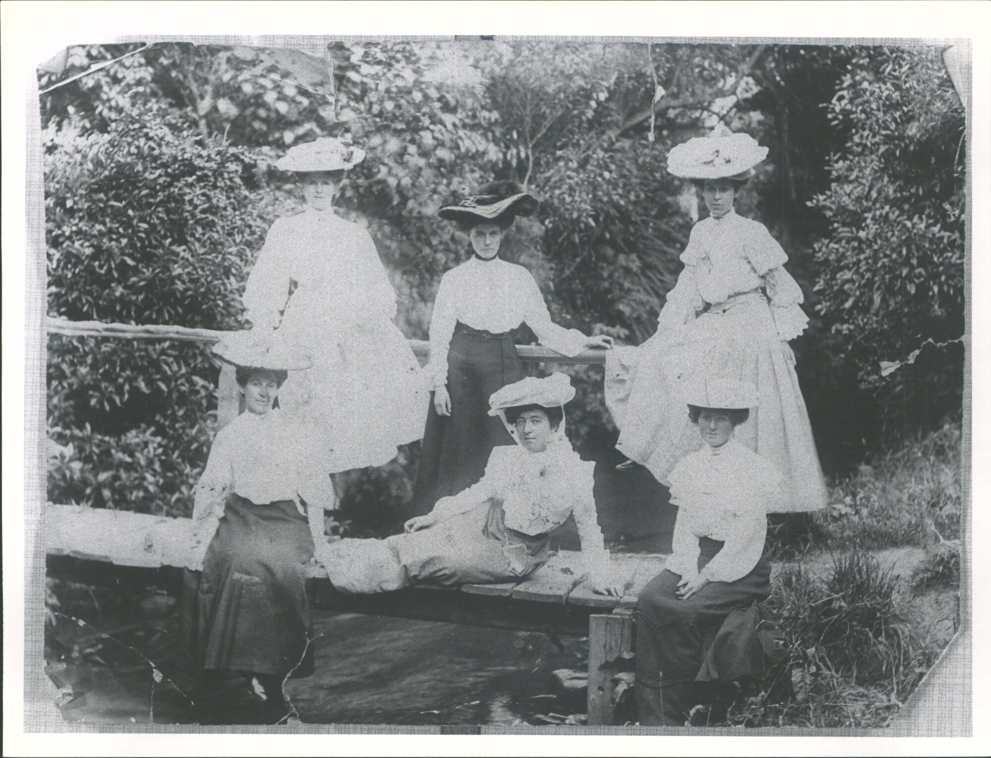 Taken on a bridge at Woodhaugh. Nell Ross of Ravensbourne in centre reclining on bridge. Others not known'