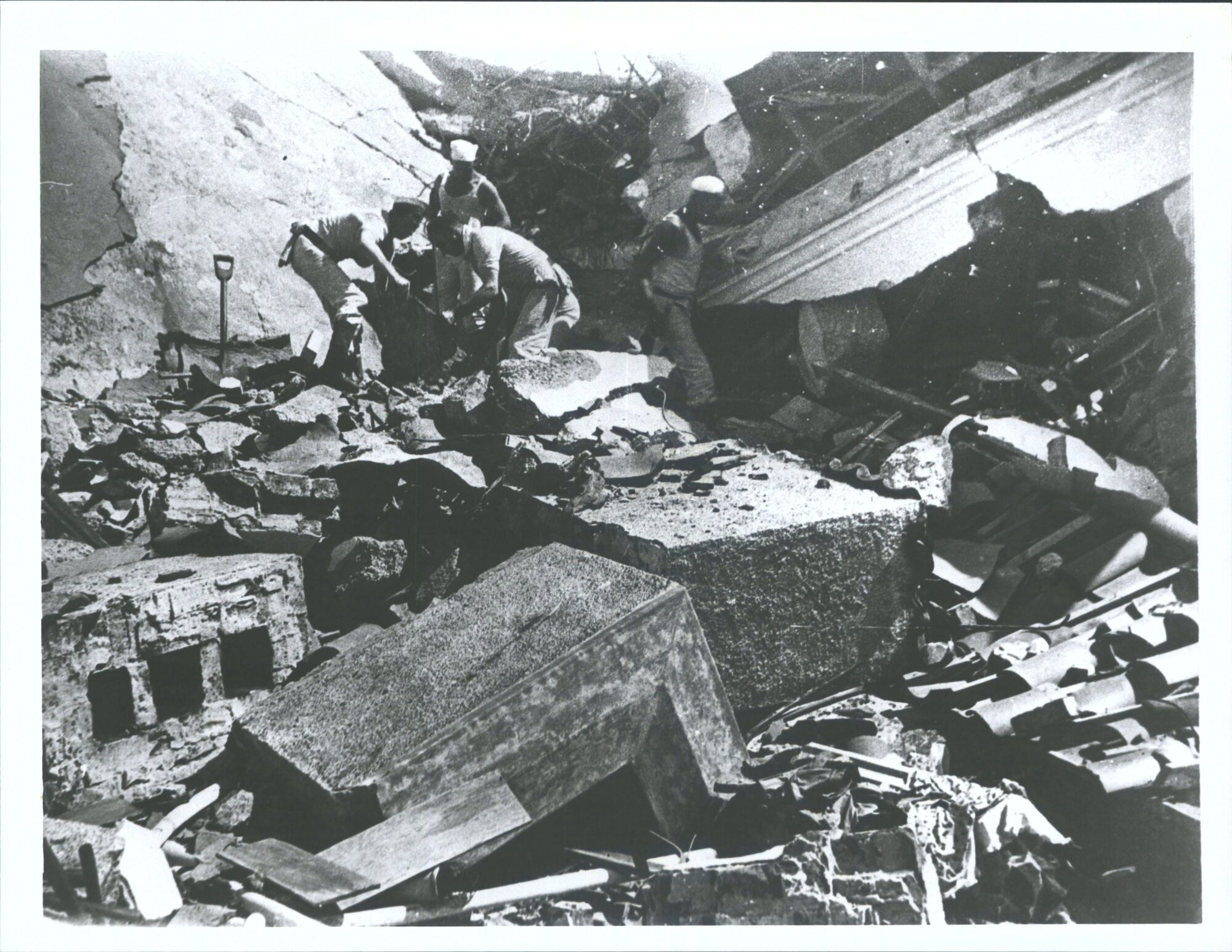 Naval men searching among ruins for bodies