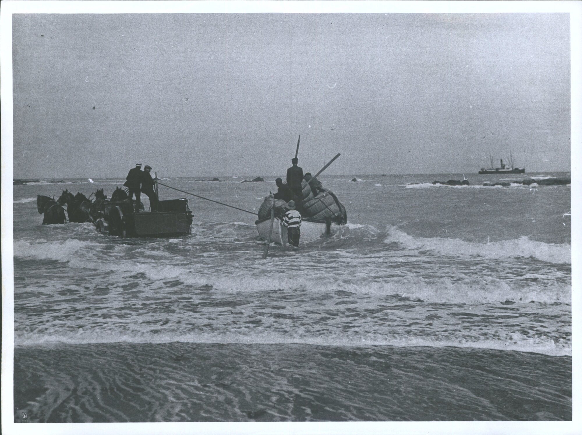 Horses pulling boat into the surf