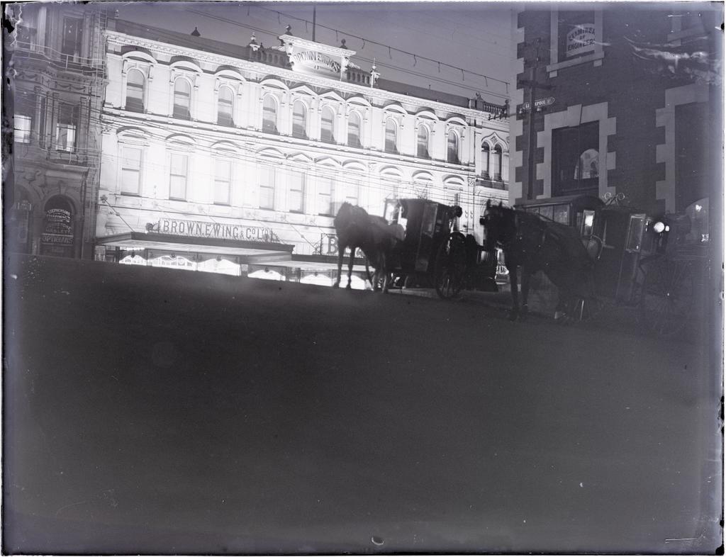 Brown Ewing and Company building and horse-drawn cabs at night, looking from Liverpool Street across Princes Street, Dunedin