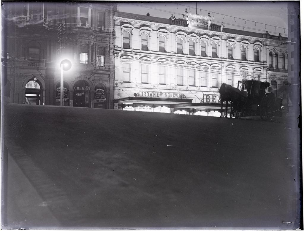Wain's Hotel and Brown Ewing and Company building at night, and horse-drawn cab, looking from Liverpool Street across Princes Street, Dunedin