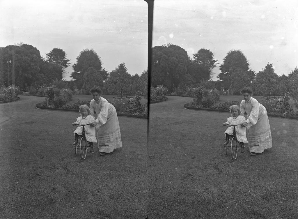 Emily on bike in driveway, held by Ethel