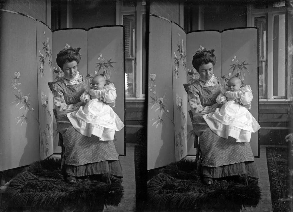 Ethel McGeorge holding Alison McGeorge in front of screen