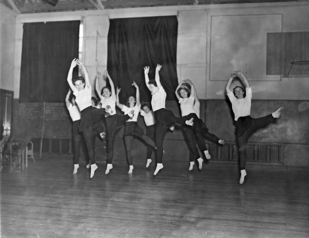 A group of ten dancers leaping