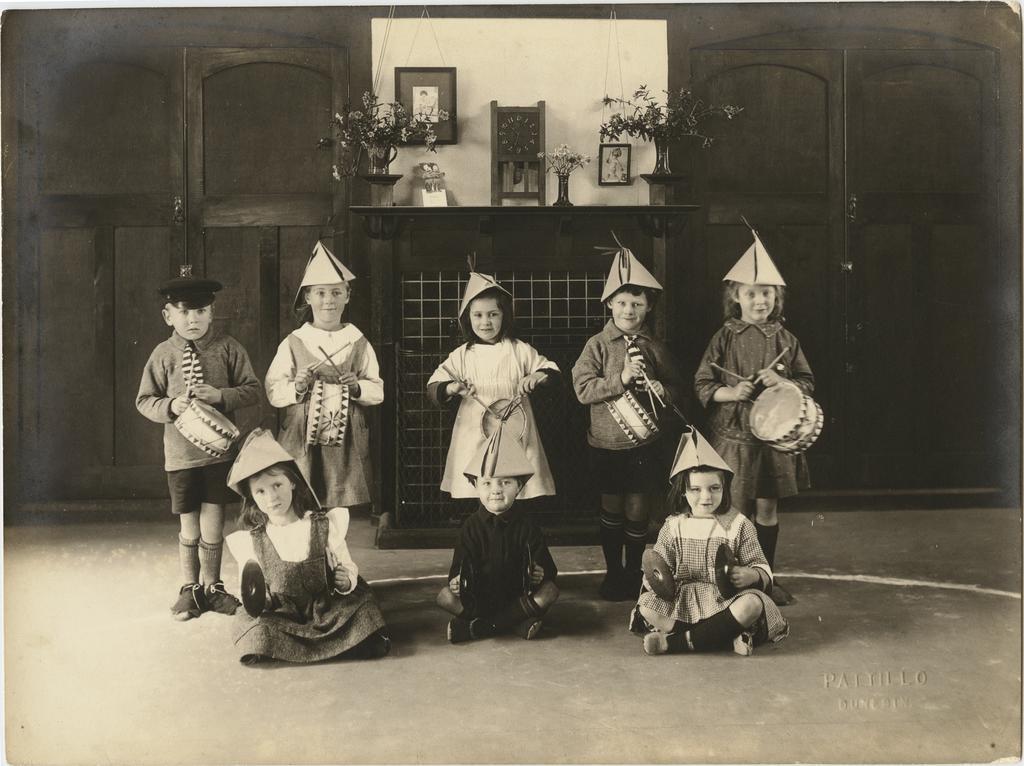 Children wearing hats, holding drums and cymbals