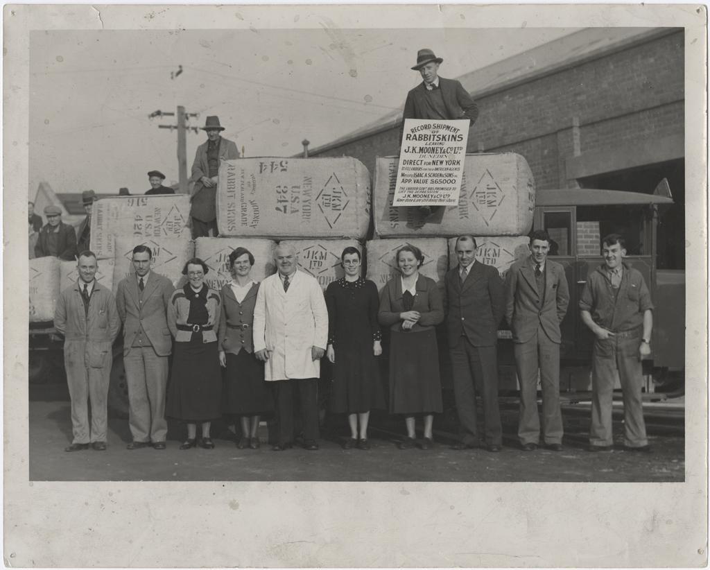 Staff members standing in front of and behind a record shipment of rabbit skins
