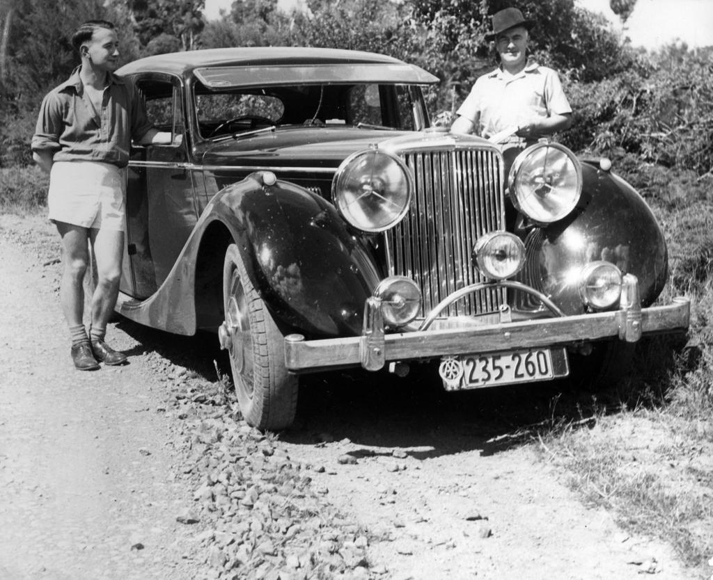 Ernie Webber with an unidentified man next to Webber's 3 1/2 litre Jaguar motor car, 'The Wicked Lady'