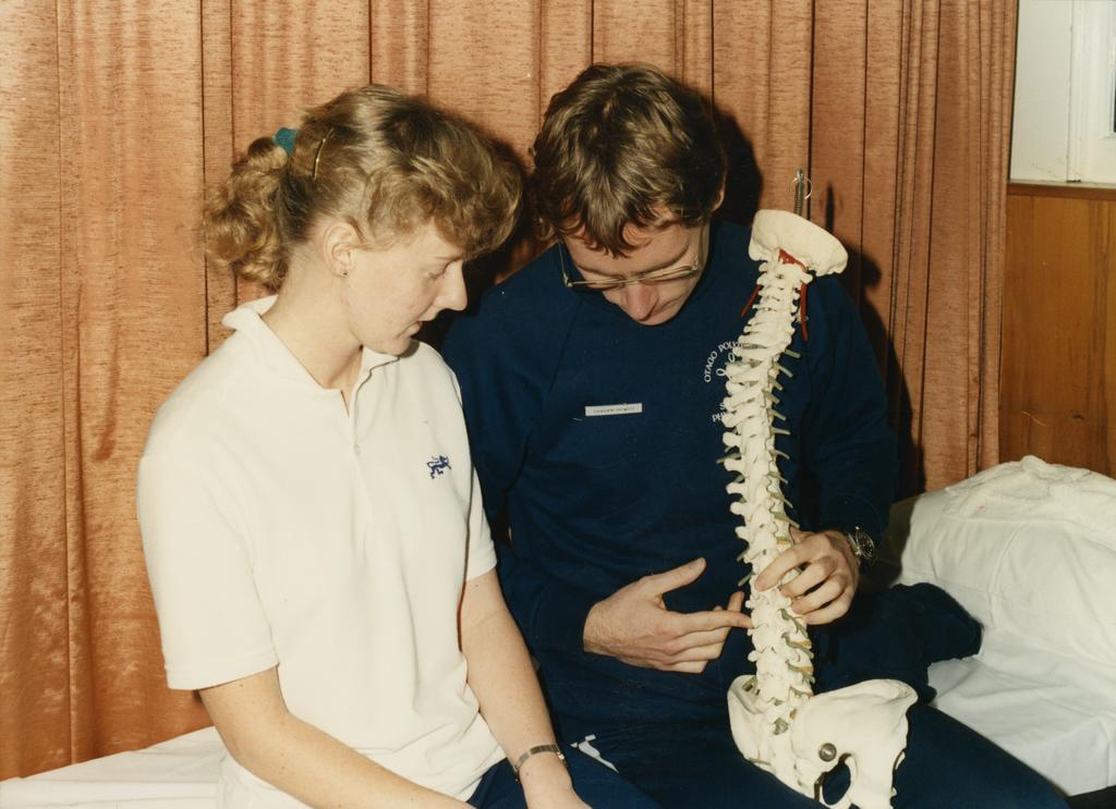 Two people looking at model of spinal cord