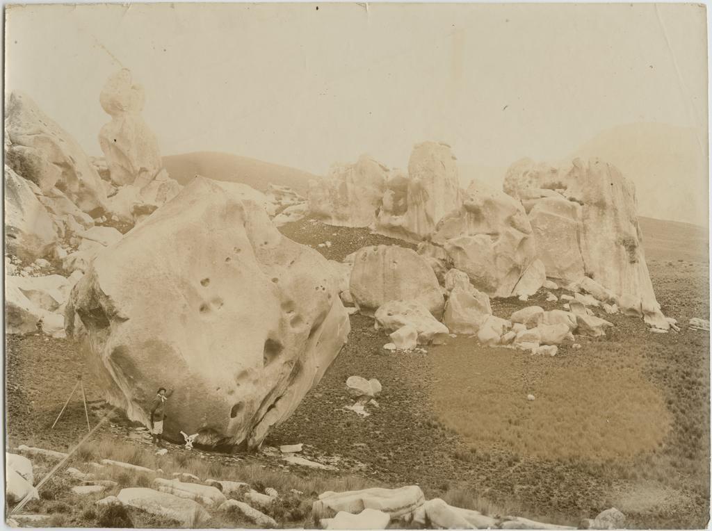 Tripod camera and man beside boulders, Castle Hill
