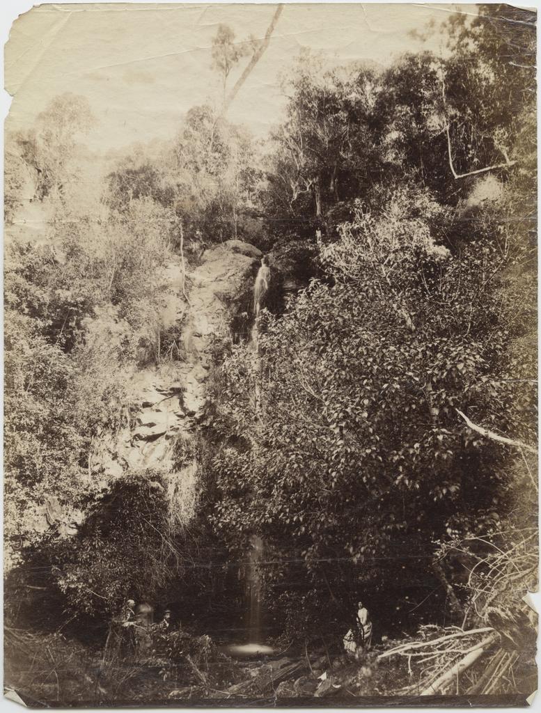 Three people at the foot of a waterfall