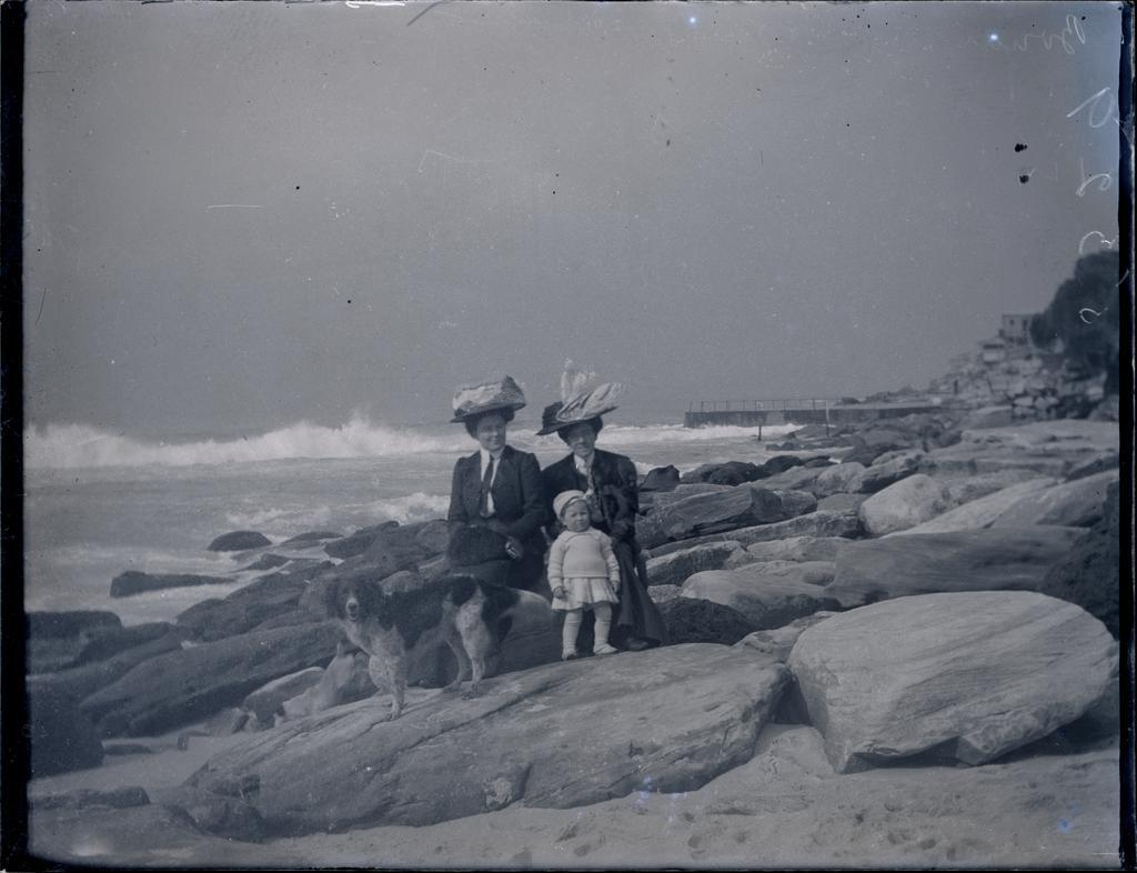 Two women, young boy and dog beside the sea