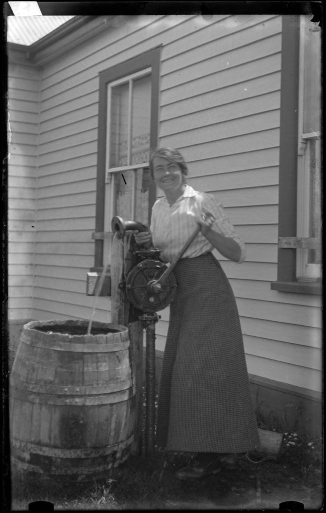 Woman pumping water into a barrel