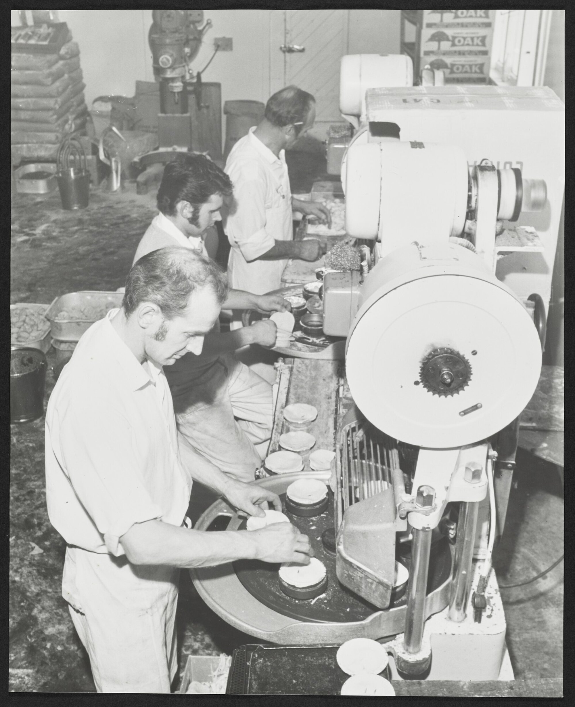 Three men at machines in Laurenson's Bakery, making pies