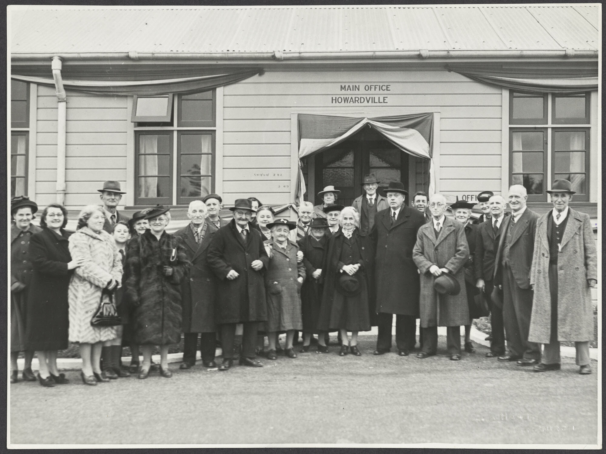Group including Mabel Howard and Peter Fraser outside the main office, Howardville, on the occasion of the official opening