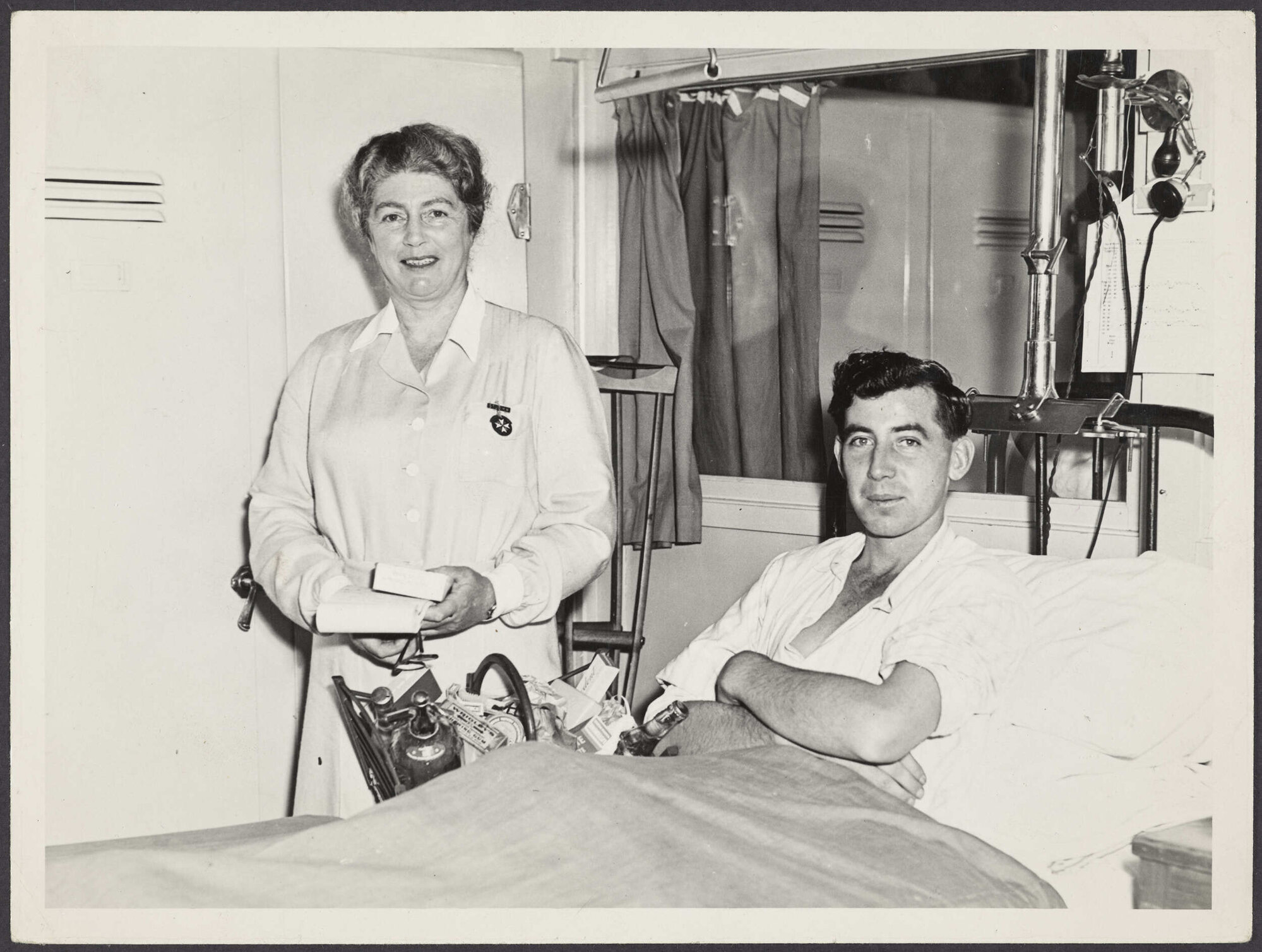 St John attendant standing next to a patient in a hospital bed