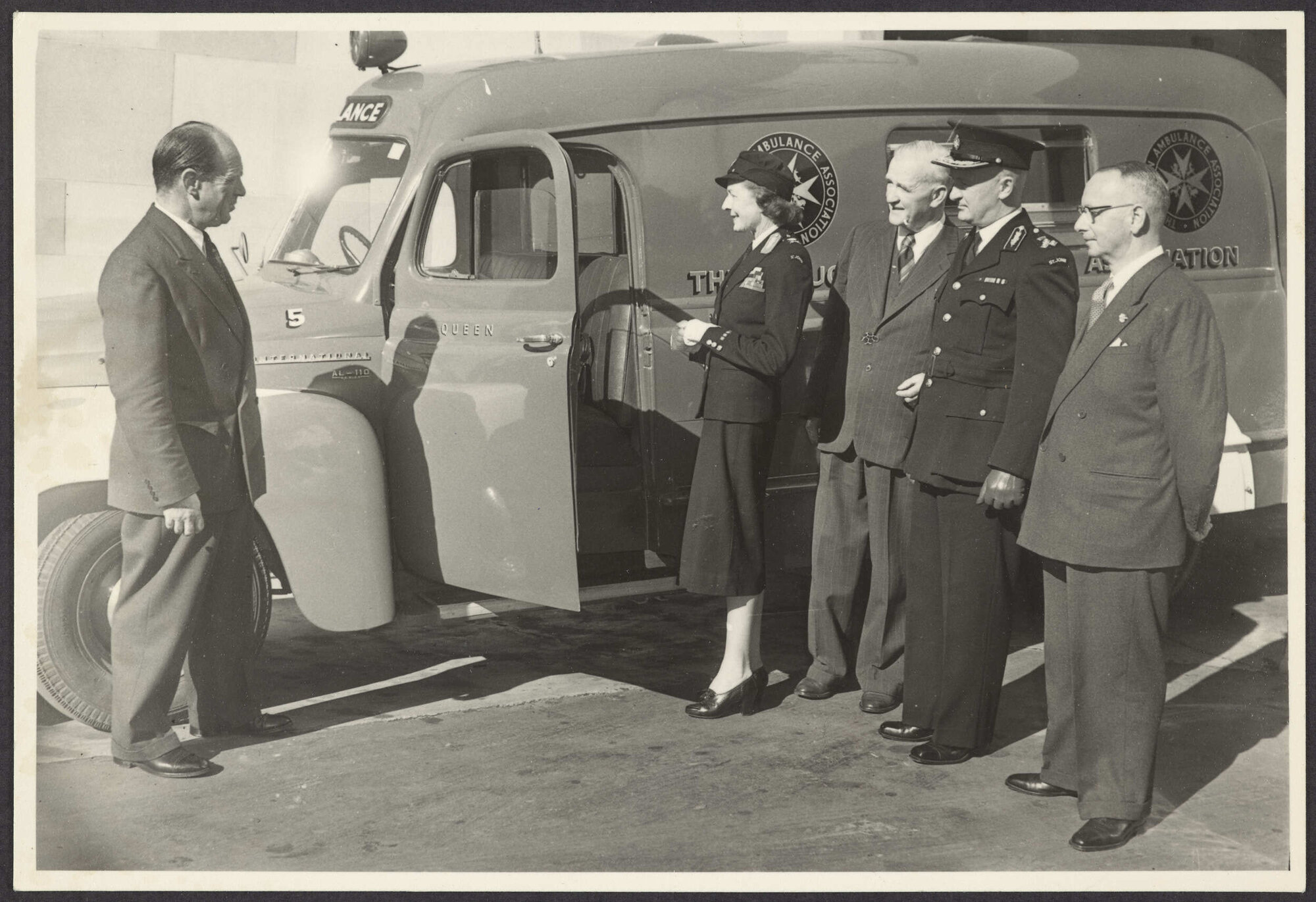 Five people standing next to St John ambulance, 'Queen'