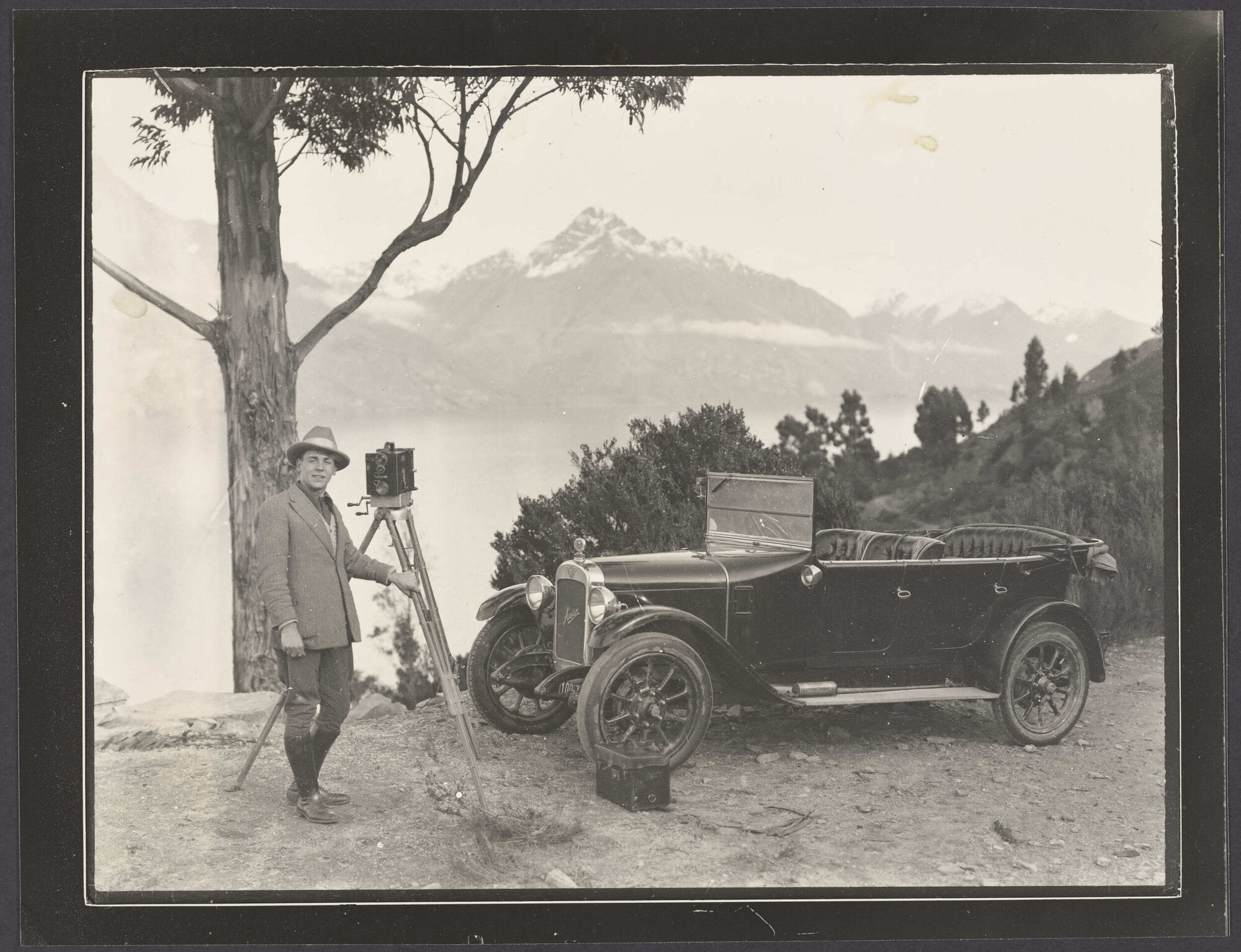 Camera operator with Austin 12 motor car in alpine lake setting