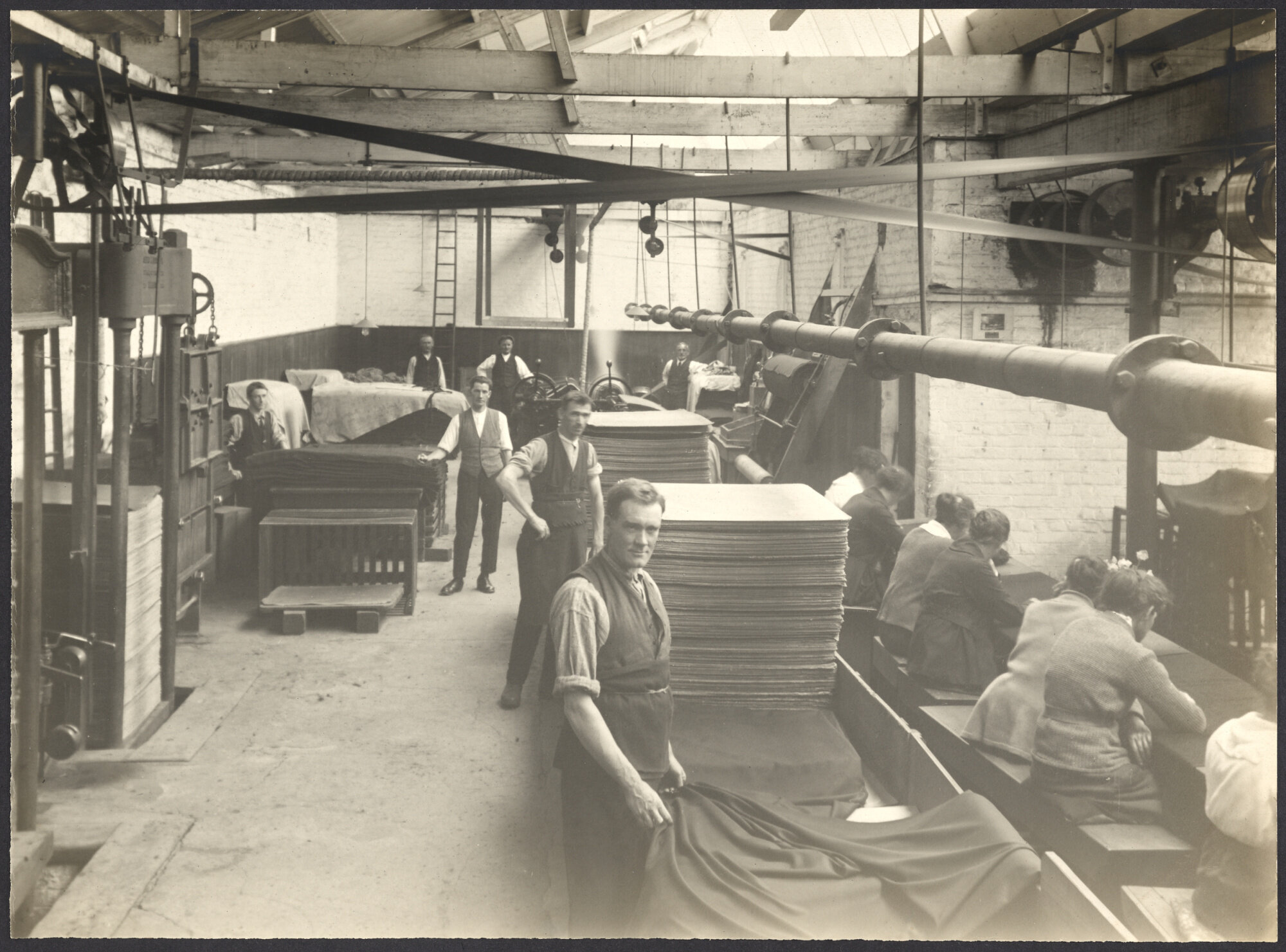 Men folding/stacking cloth and women darning cloth