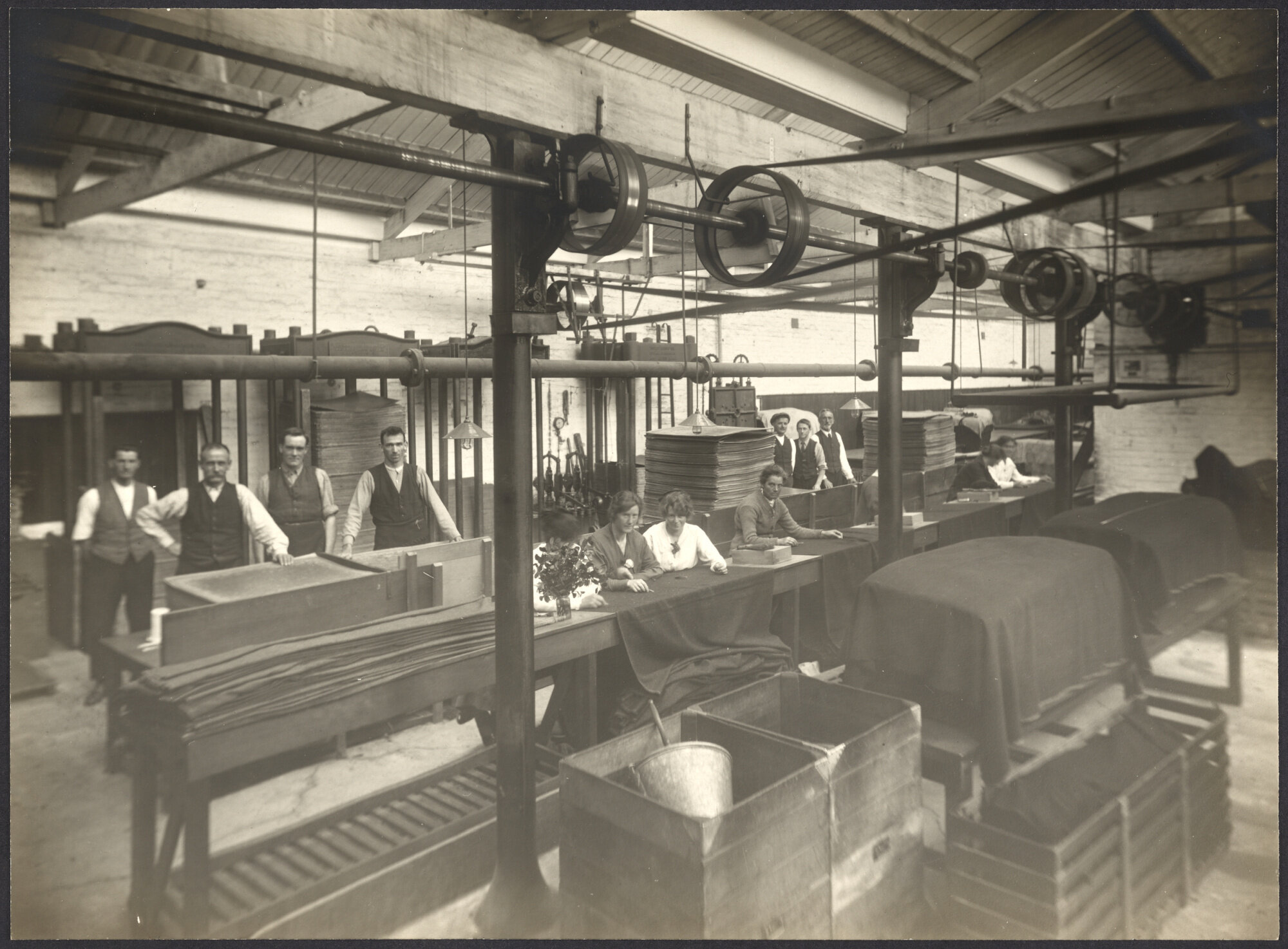 Workers darning cloth at sloping tables