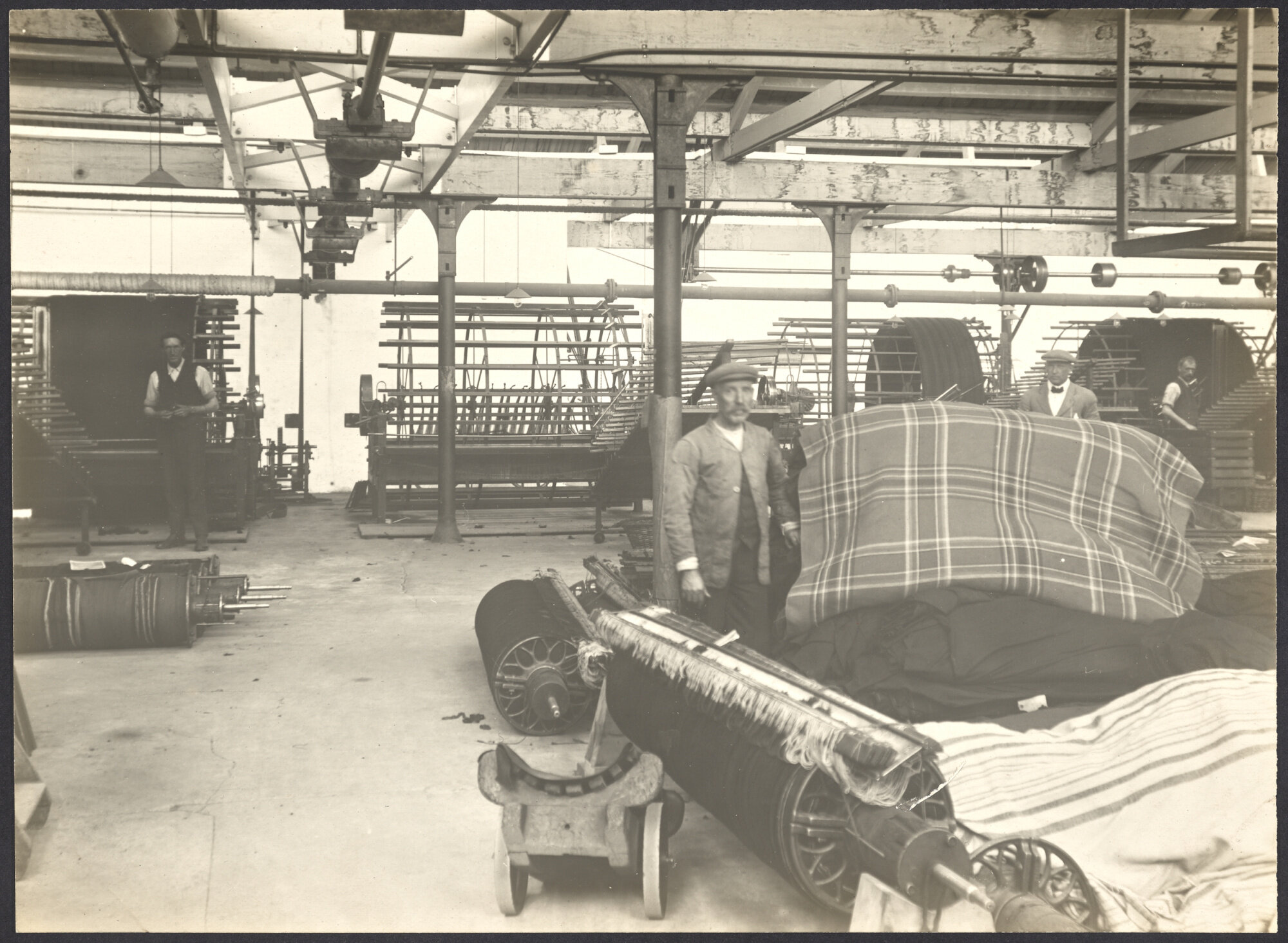 Male workers with piles of blankets and warping looms