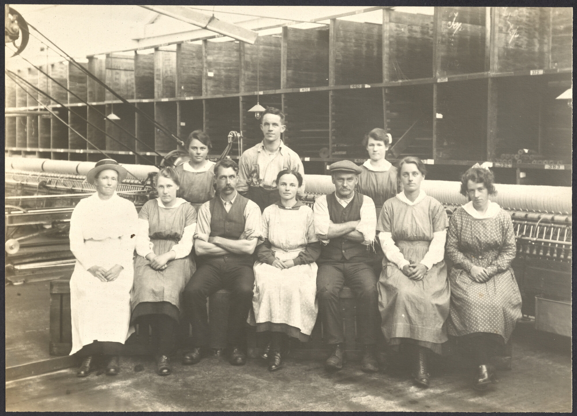 Staff group seated in front of spinning mule machinery
