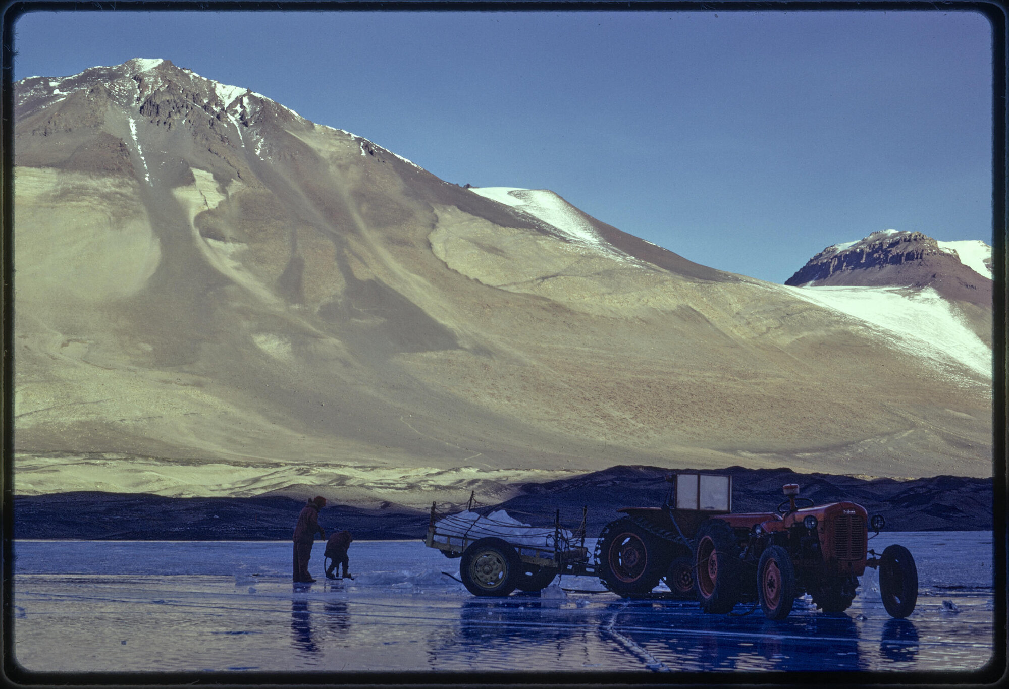 Cutting ice for ice melter, with Mt Odin and Jeremy Sykes Glacier in background'.