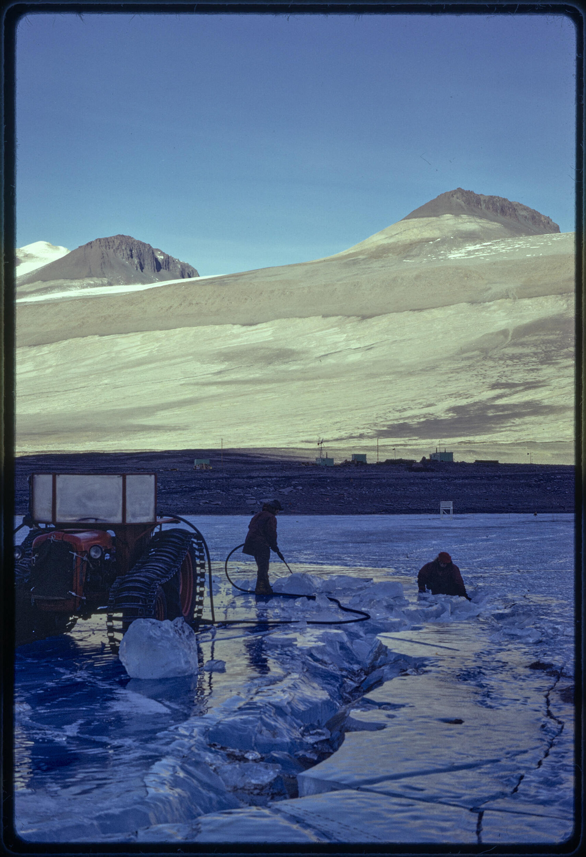 Cutting ice early winter for station ice melter, station seen in mid-distance