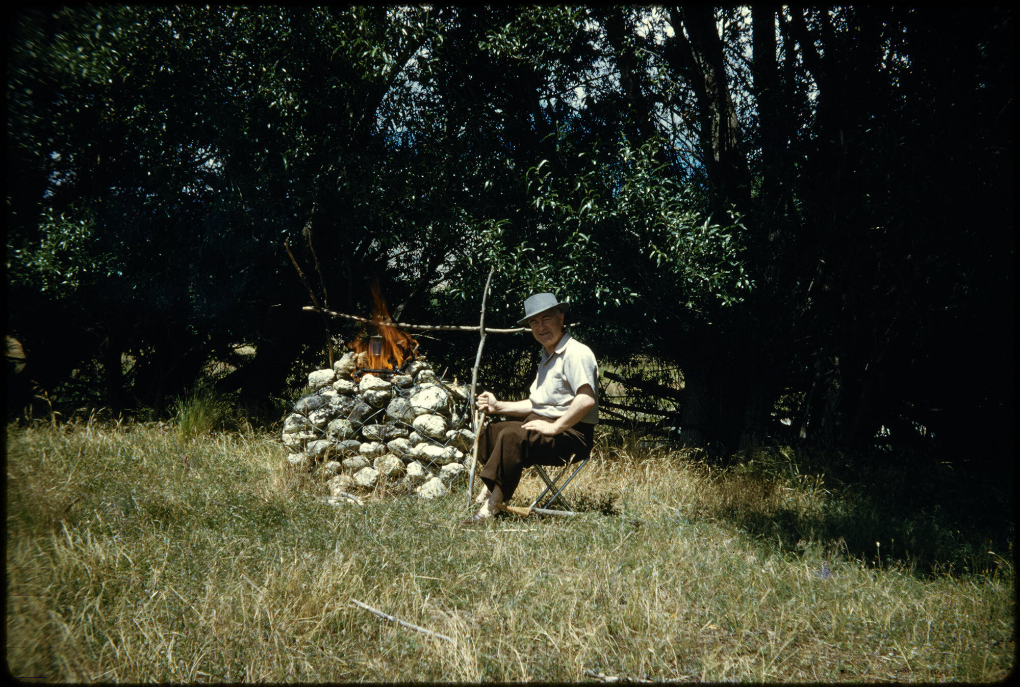 Ernie Webber beside a campfire