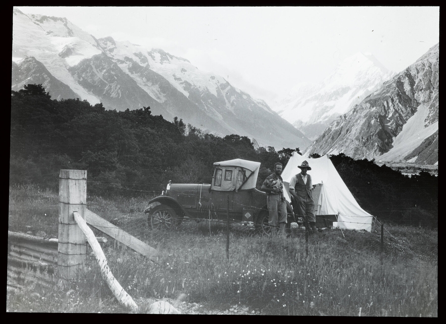 Two people standing next to a car at a camp in the Hooker Valley