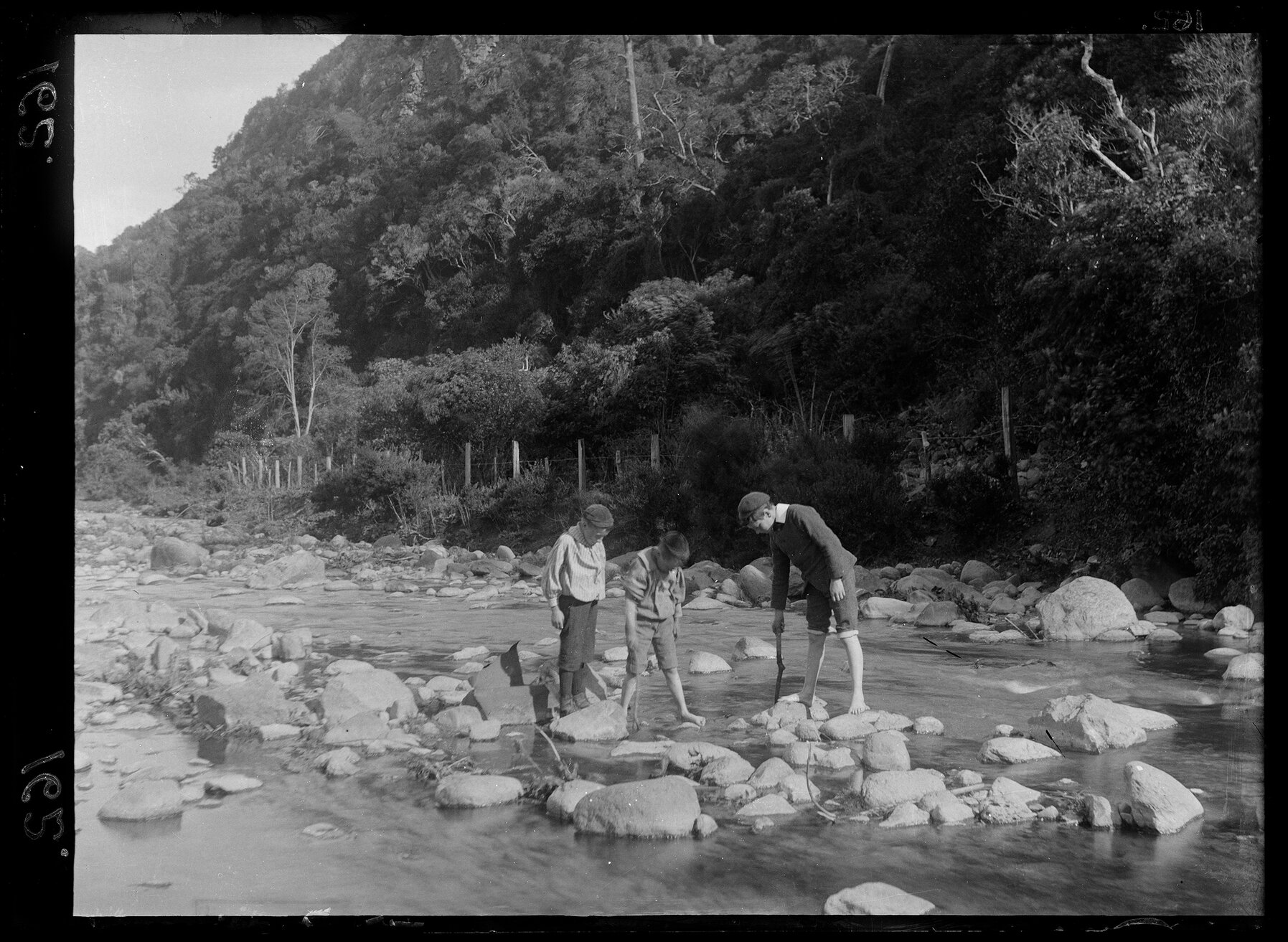 Three boys playing in a stream