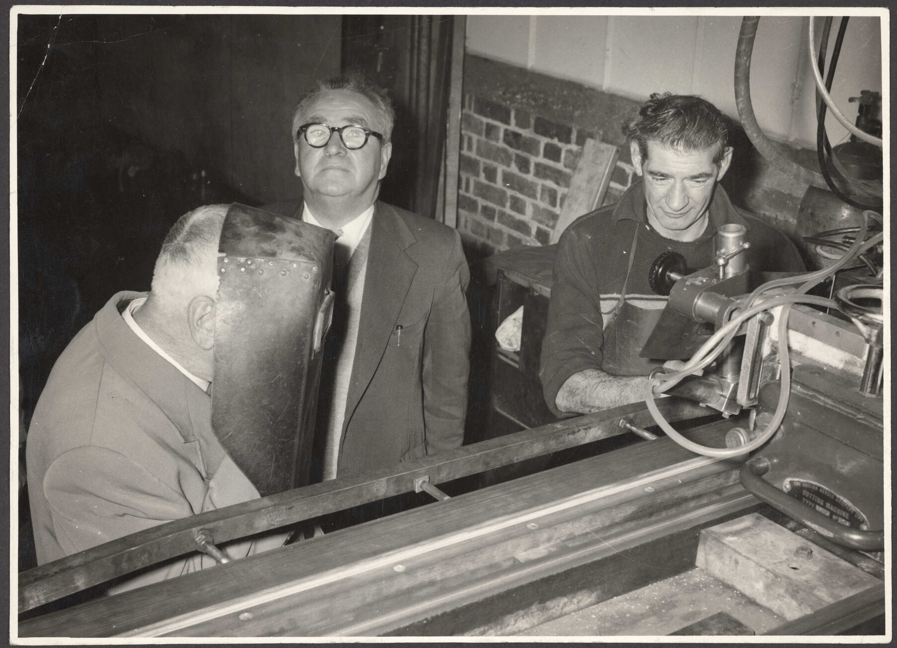 Walter Nash, Thomas Marlowe, and Don Lumb with cutting machine at J. &amp; W. Faulkner factory