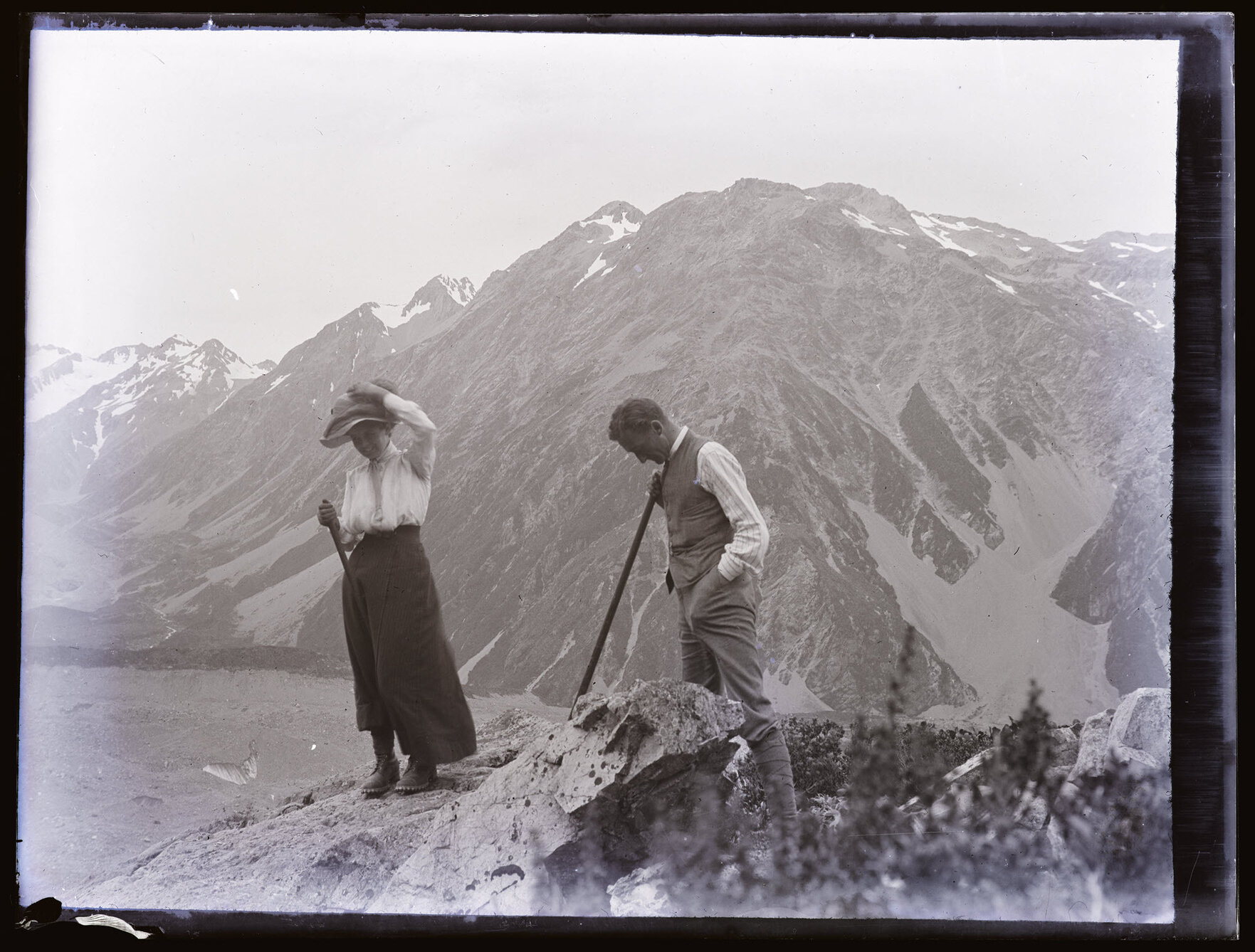 Two people on a rock outcrop above glacial moraine
