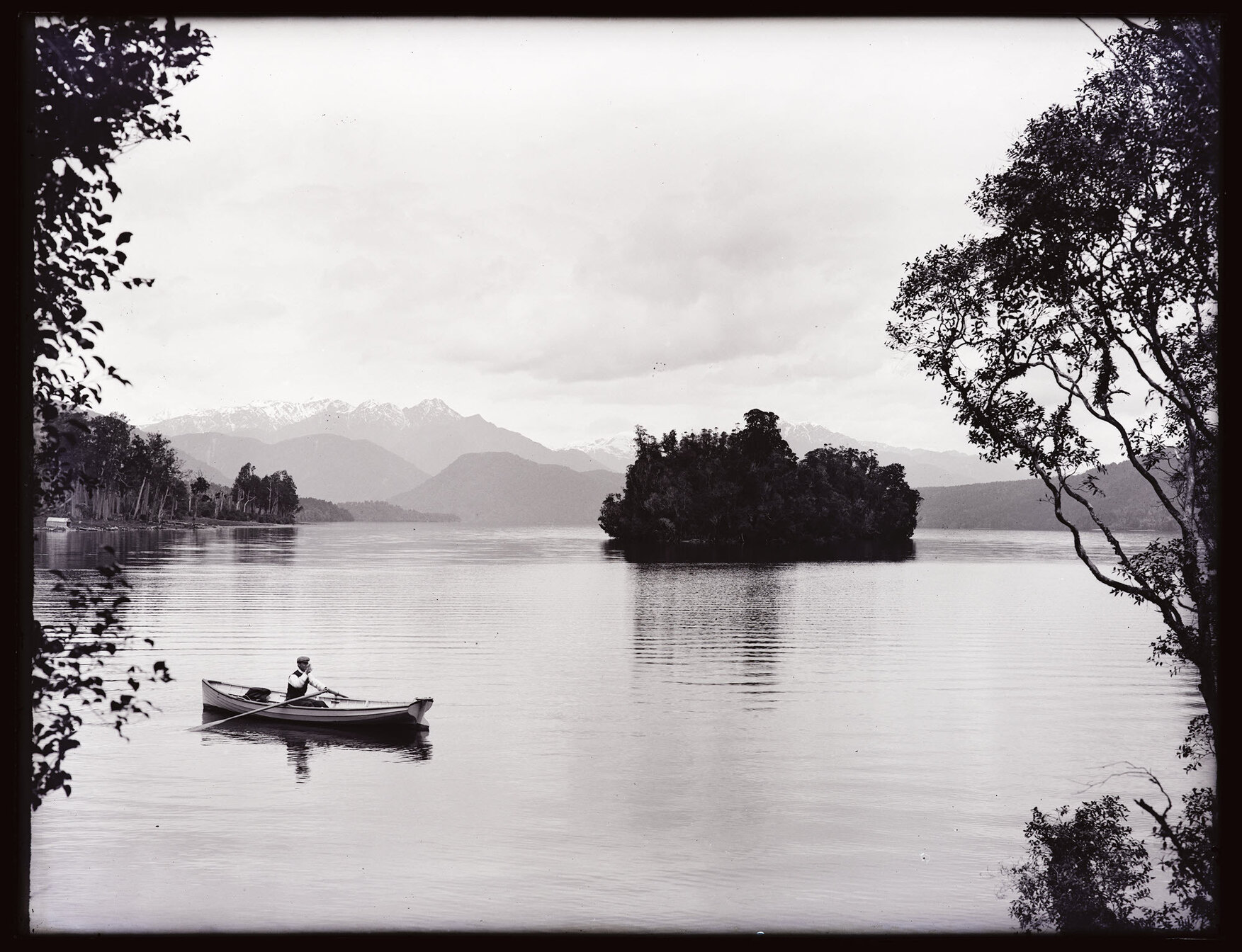 Unidentified body of water with small island, and person rowing boat