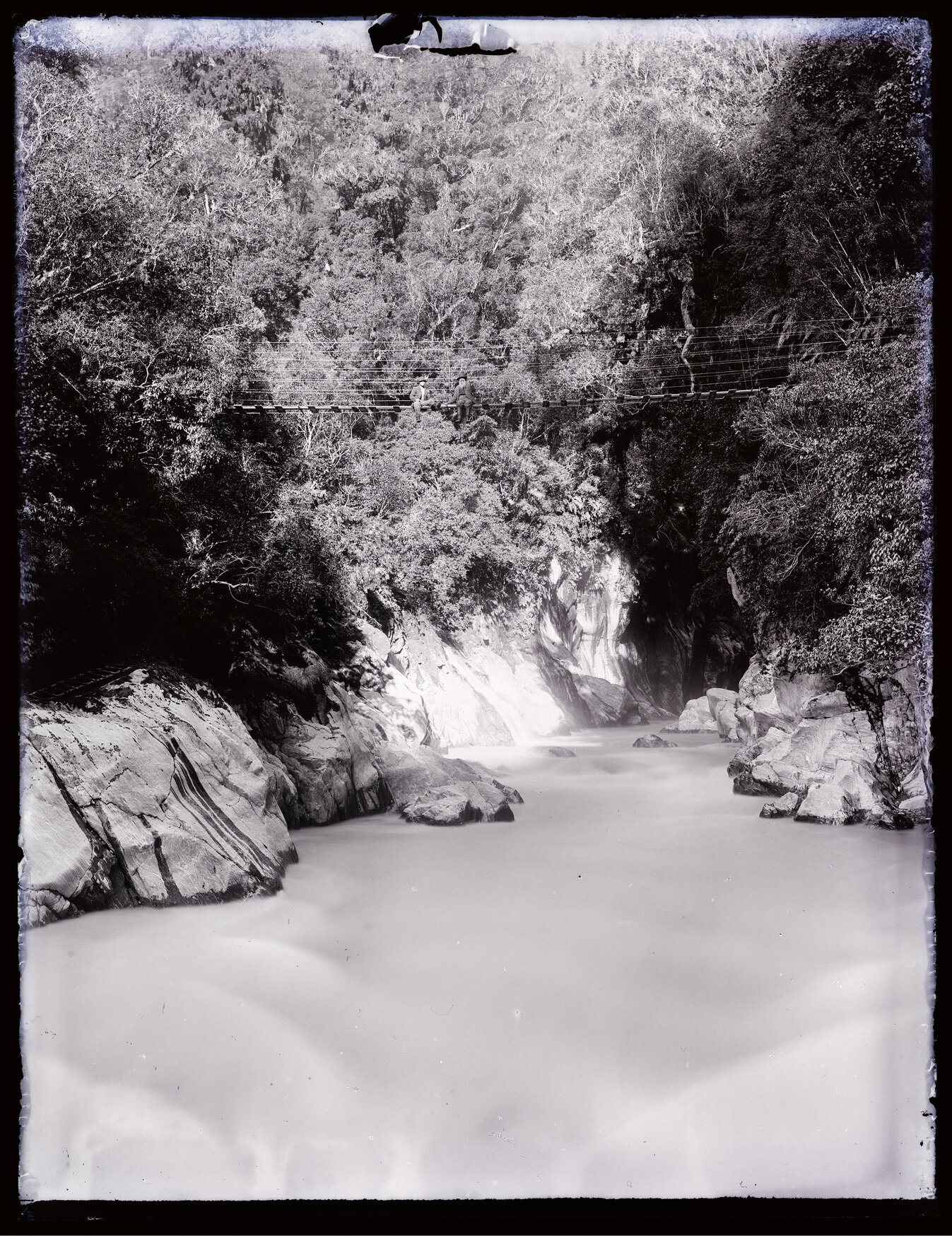 Two people sitting on a bridge over a river gorge, Westland 