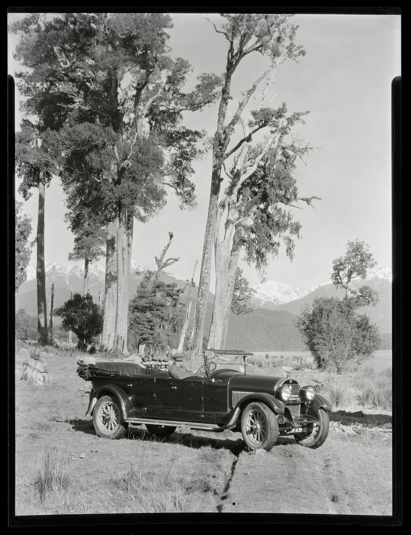 Driver at the wheel of a Newmans Motors car with biplane bonnet ornament 