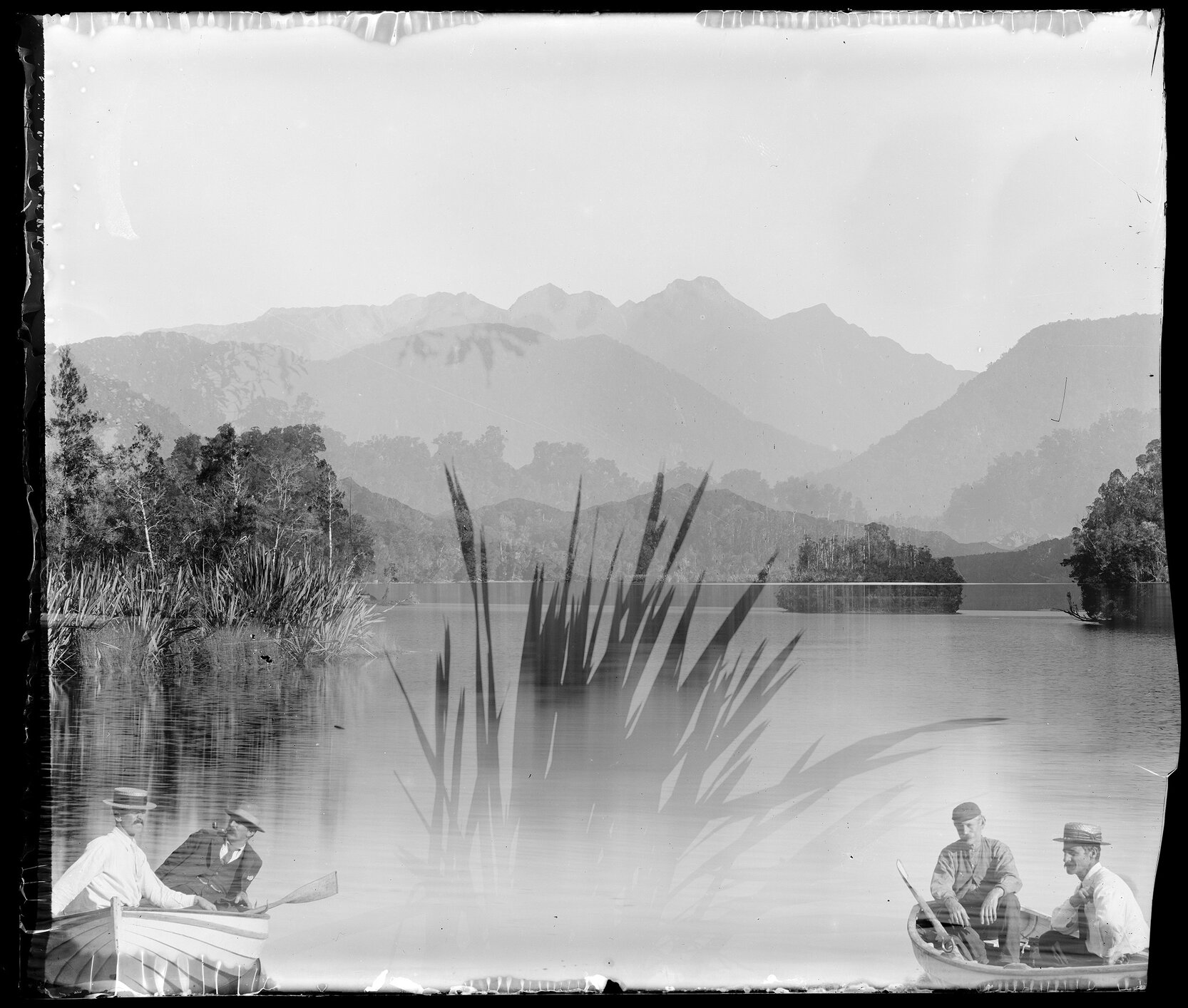 Four people in boats, with view across water to mountains