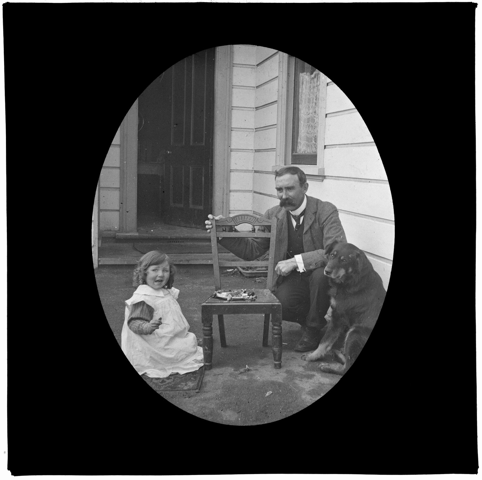 Young girl, man, and dog, next to a small chair