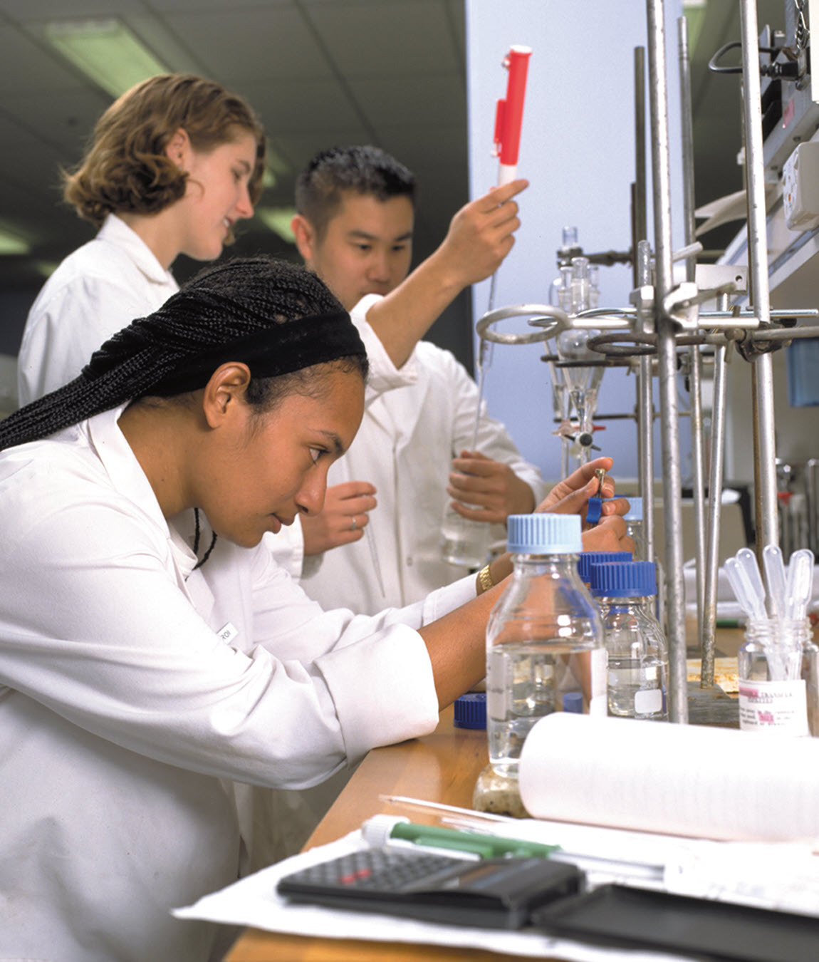 Three students using laboratory equipment