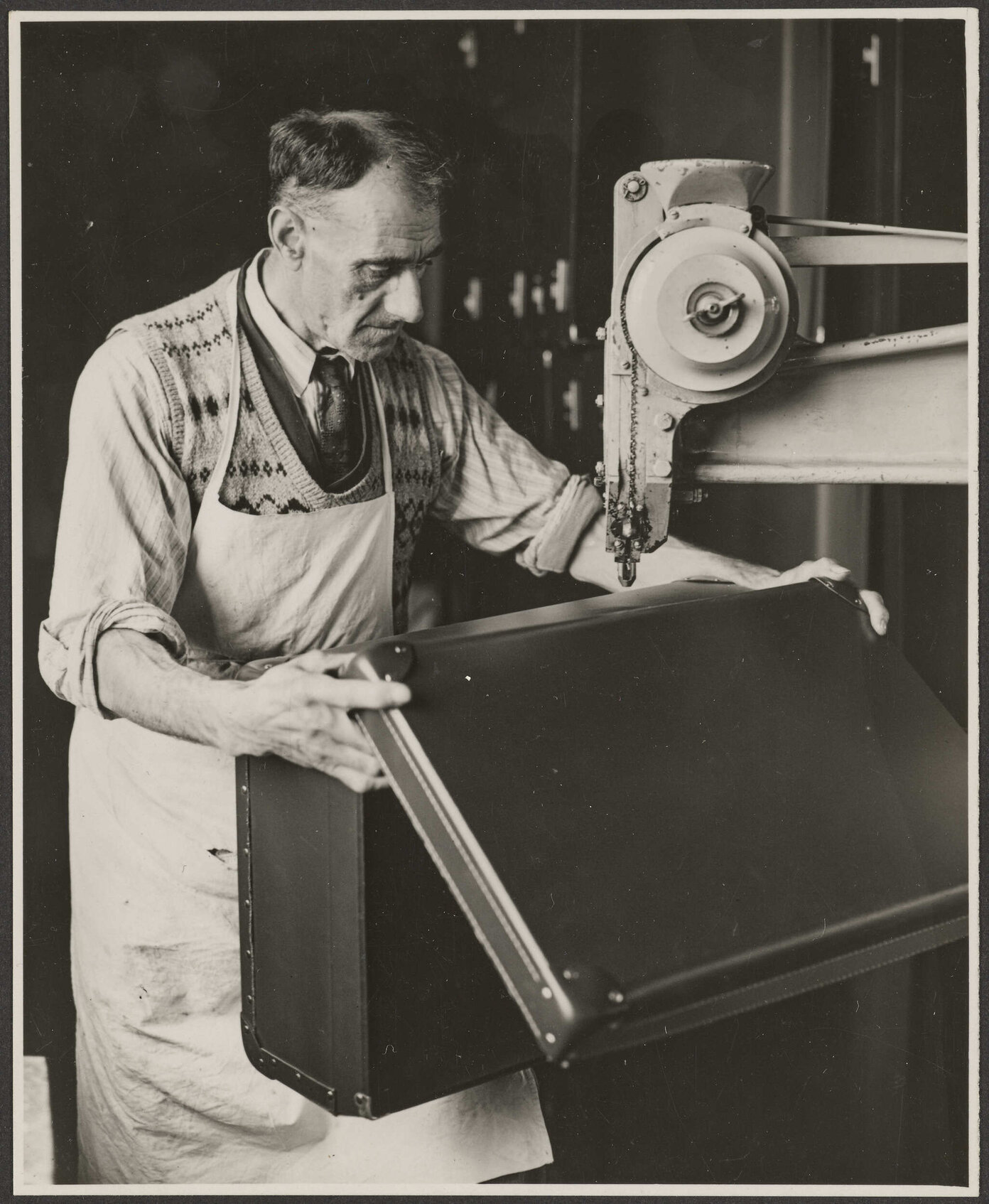 Worker putting the final rivets in a suitcase