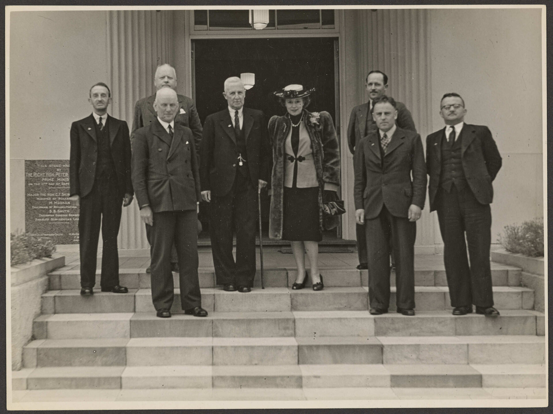 Nola Luxford and group of men on the steps of the Disabled Servicemen's Re-establishment League, Dunedin Centre