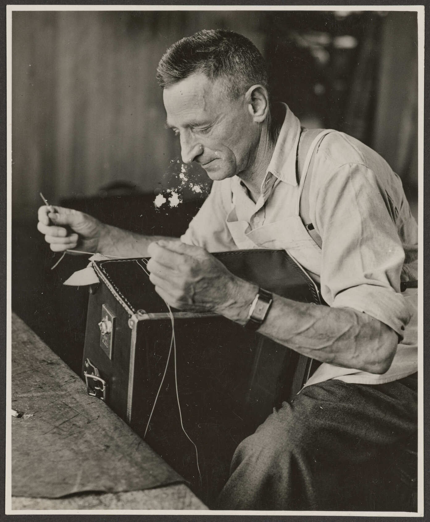 Worker stitching a suitcase