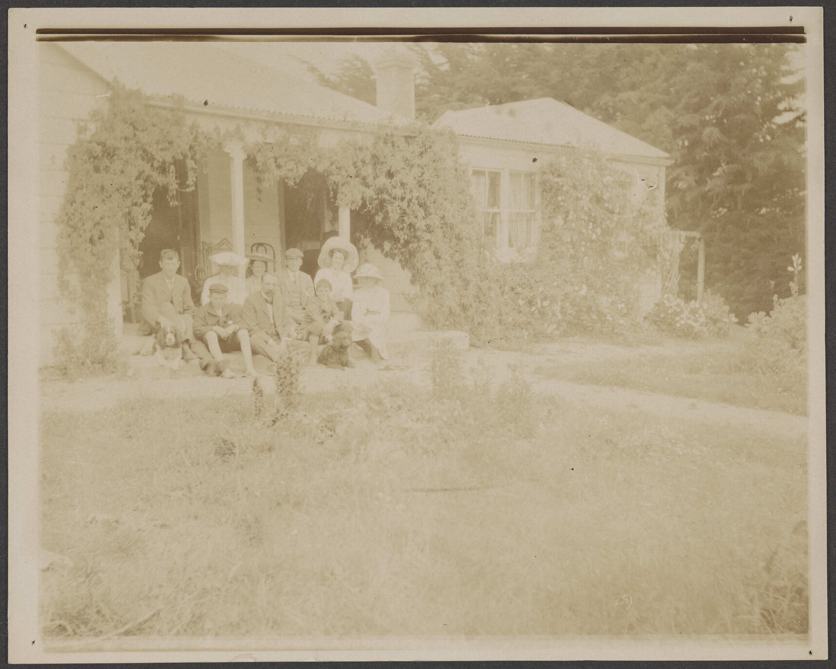 Family group seated in front of house